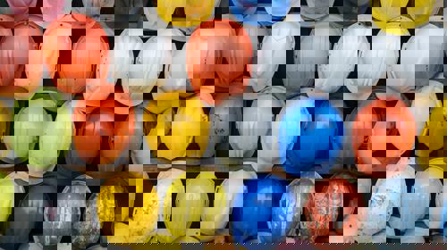Dozens of different coloured hard hats hung up on a rack