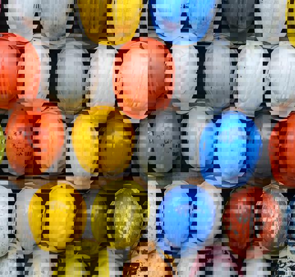 Dozens of different coloured hard hats hung up on a rack