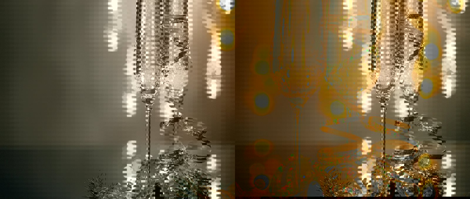 Champagne glasses on a table with festive lights in the background