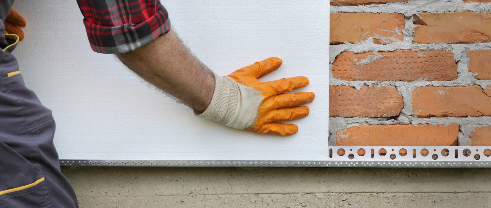 Close-up photograph of someone fitting insulation panels on a brick wall