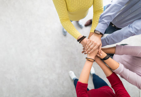 Overhead photograph of four people clasping their hands together