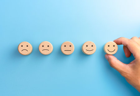 Photograph of five small wooden disks each printed with a face. The range from unhappy to happy expressions going from left to right. 