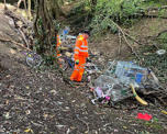 One of our team in orange hi-vis clothing getting ready to clean up some dumped shopping trolleys
