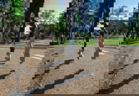 Close up photo of a woman's lower legs and feet taken as she jogs along a pathway in a park