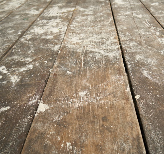 Photo of old, brown, dusty wooden floorboards with a slight gap in between