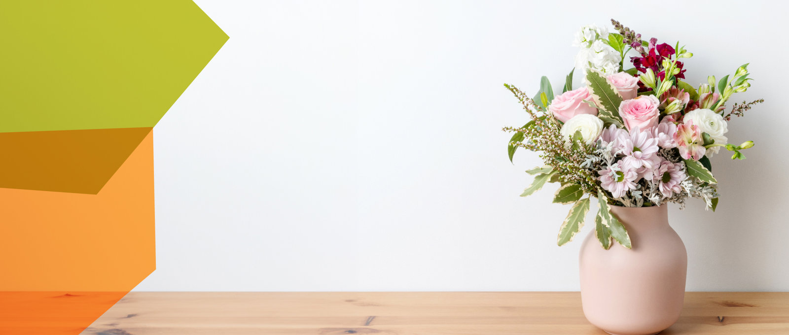 Photo of a fresh bunch of flowers in a vase on a wooden shelf.
