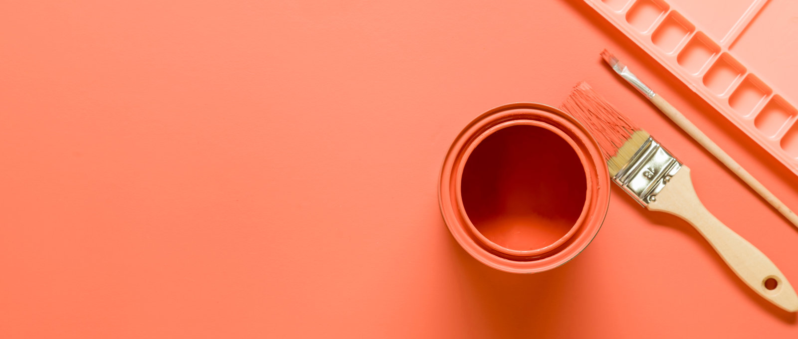 Stylised photo of a paint pot. palette and paint brushes, all pink and lying on a pink surface
