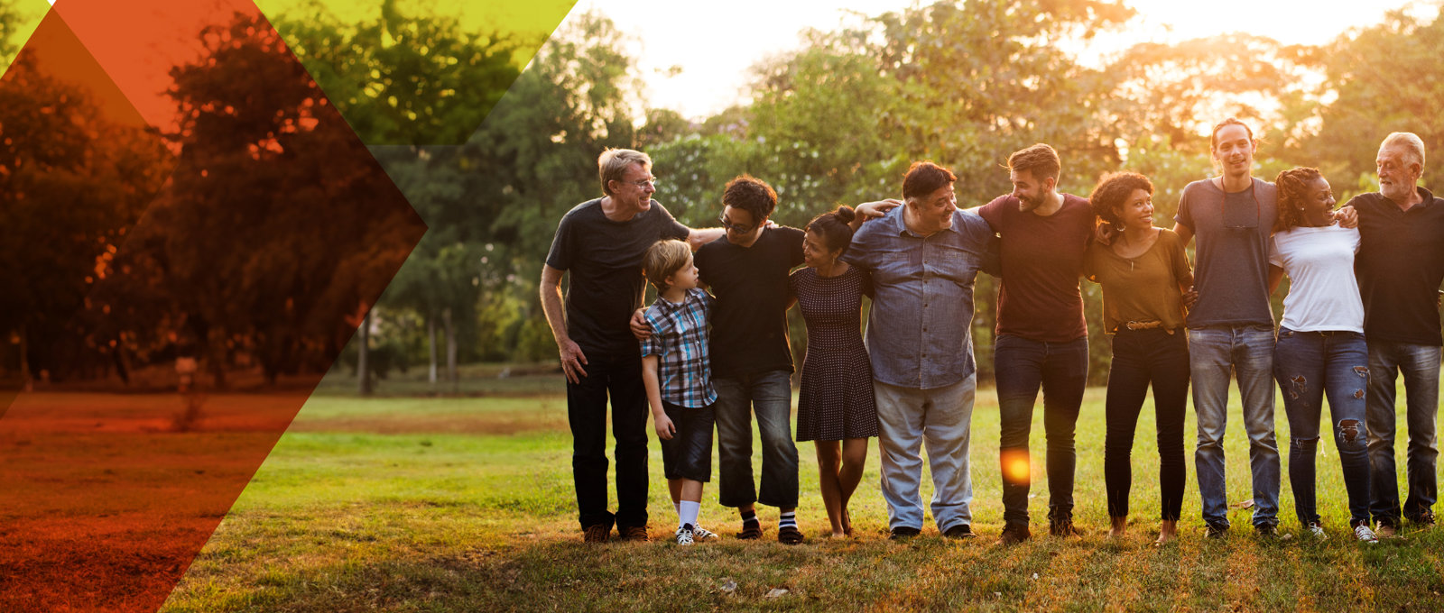 Photo of a line-up of around a dozen people with their arms linked standing against a woodland background on a sunny day